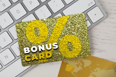 Image of Bonus card with stylish design and computer keyboard on white wooden table, top view