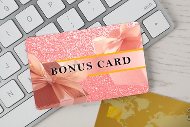 Image of Bonus card with stylish design and computer keyboard on white wooden table, top view