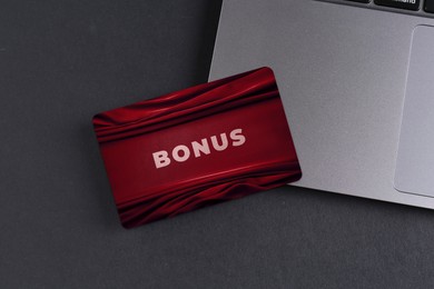 Image of Bonus card with stylish design and laptop on grey table