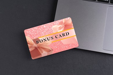 Image of Bonus card with stylish design and laptop on grey table