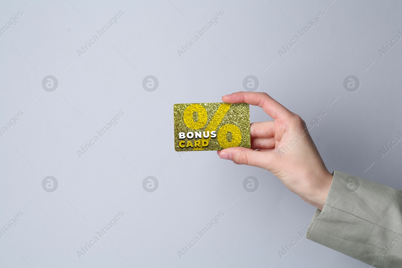 Woman holding Bonus card with stylish design on grey background, closeup Image of Woman holding Bonus card with stylish design on grey background, closeup