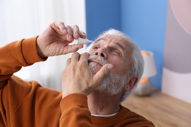 Photo of Senior man applying eye drops at home