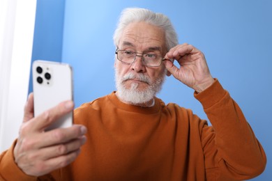 Photo of Senior man with vision problem using smartphone at home