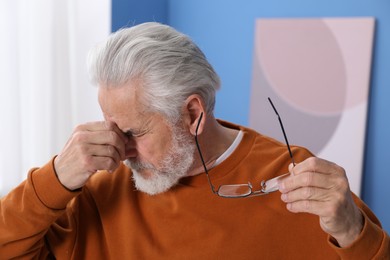 Photo of Senior man with glasses suffering from eyestrain at home