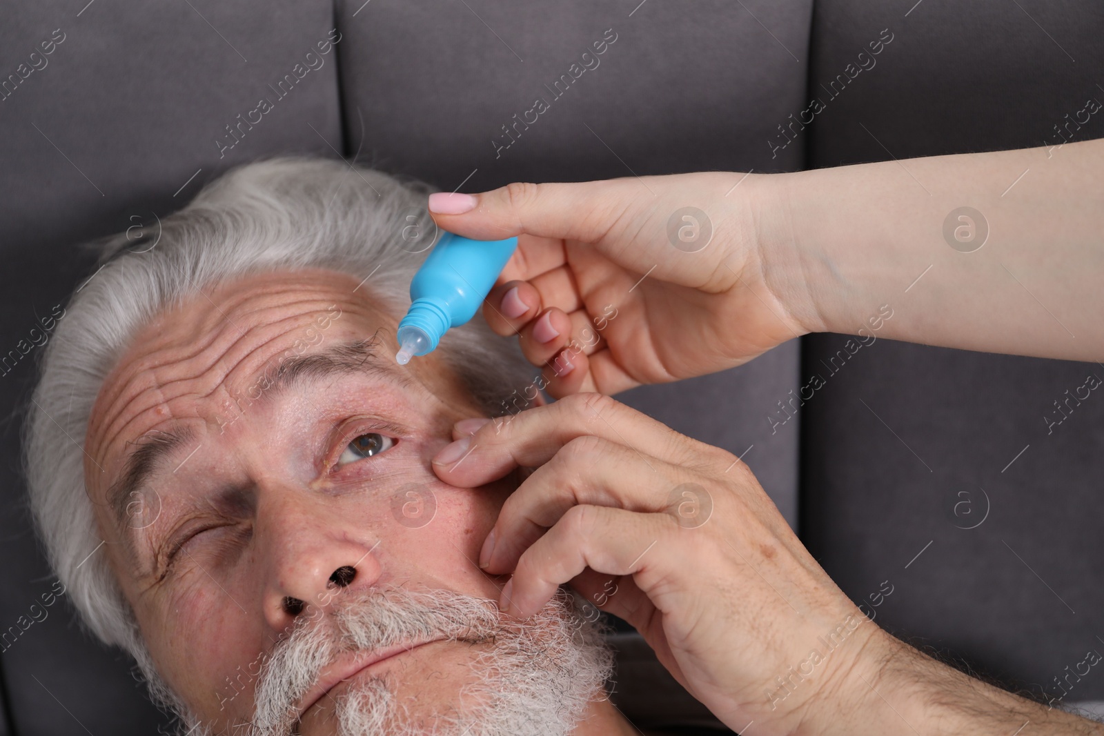 Woman dripping medication into man's eye at home, closeup Photo of Woman dripping medication into man's eye at home, closeup