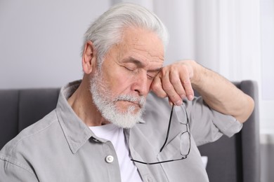 Photo of Senior man with glasses suffering from eyestrain at home