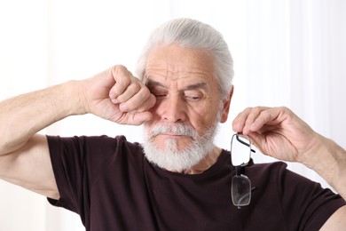 Photo of Senior man with glasses suffering from eyestrain at home