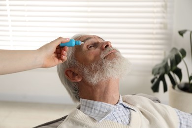Photo of Woman dripping medication into man's eye at home, closeup