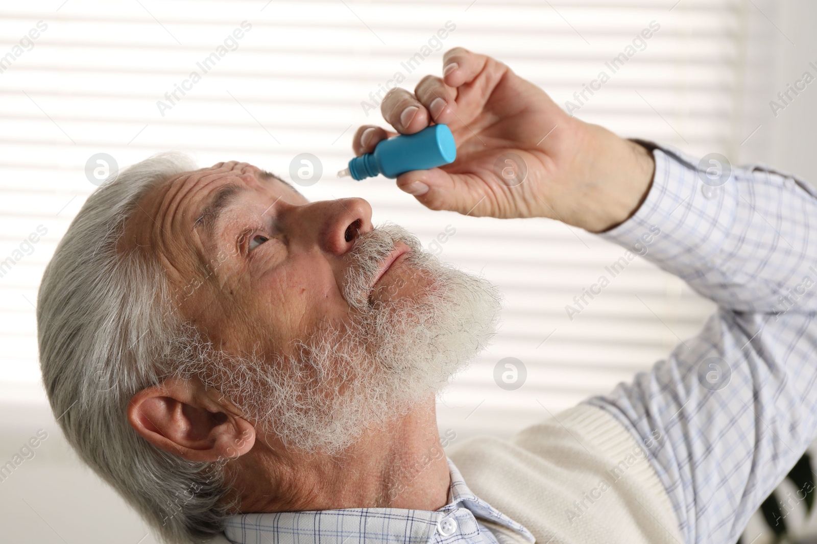 Senior man applying eye drops at home Photo of Senior man applying eye drops at home