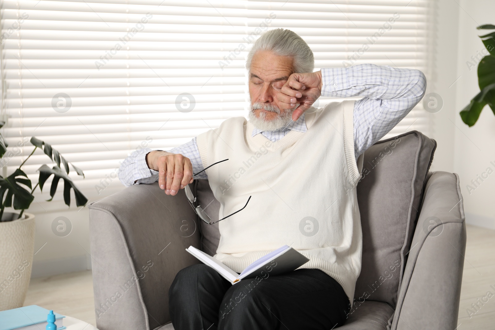 Senior man with glasses suffering from eyestrain in armchair at home Photo of Senior man with glasses suffering from eyestrain in armchair at home