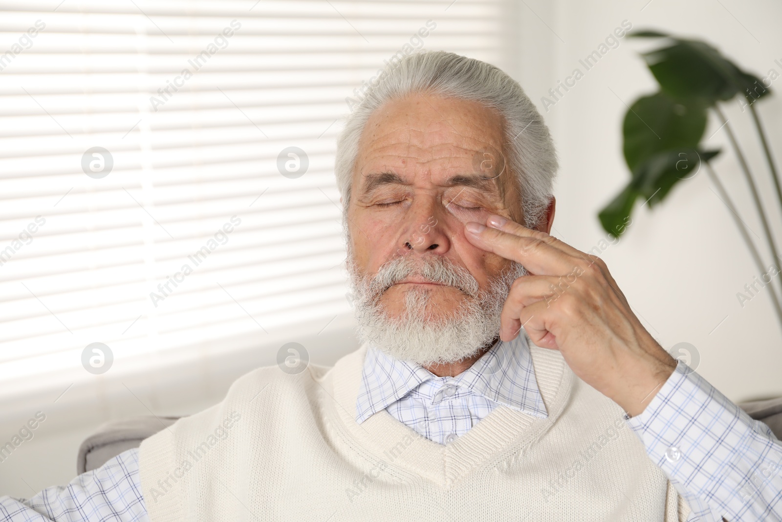 Senior man suffering from eyestrain at home Photo of Senior man suffering from eyestrain at home