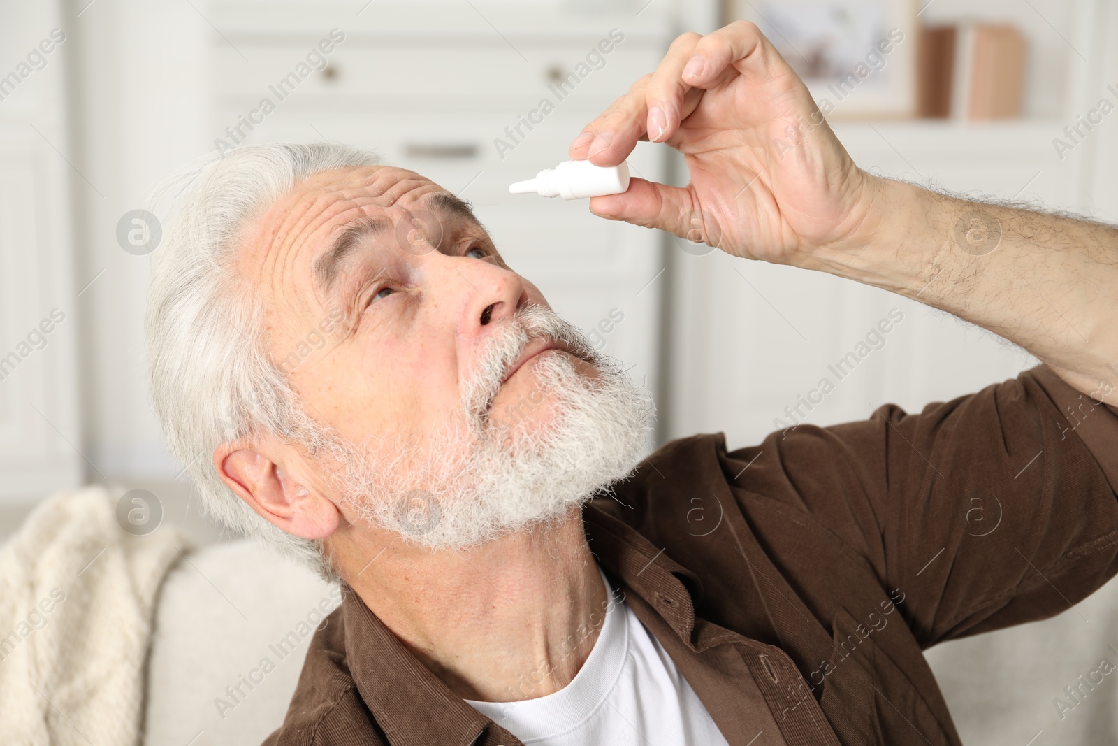Senior man applying eye drops at home Photo of Senior man applying eye drops at home