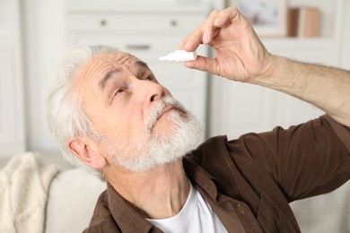 Photo of Senior man applying eye drops at home