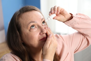 Photo of Woman with vision problem applying eye drops at home