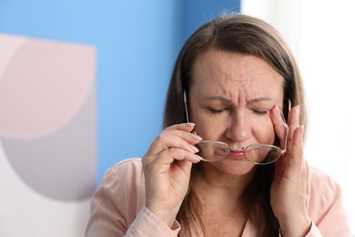 Photo of Woman with glasses suffering from eyestrain at home, space for text