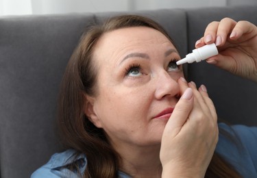 Photo of Woman applying eye drops on bed at home