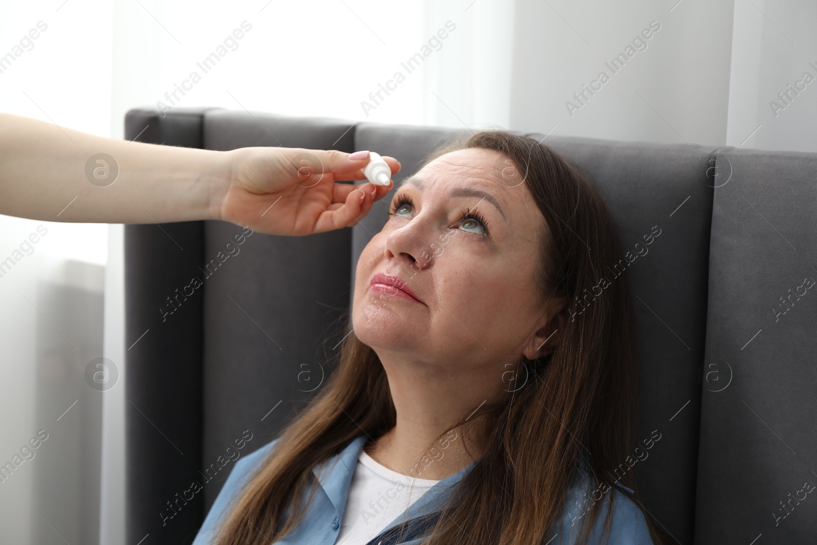 Daughter dripping medication into mother's eye at home, closeup Photo of Daughter dripping medication into mother's eye at home, closeup