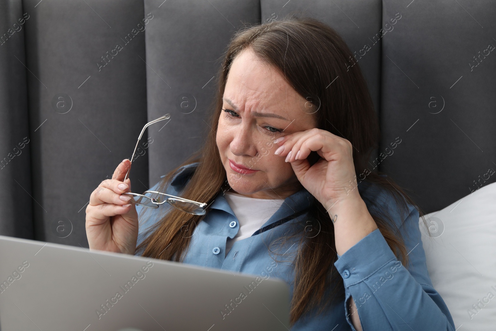 Woman with vision problem using laptop on bed at home Photo of Woman with vision problem using laptop on bed at home