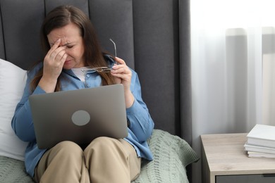 Photo of Woman with vision problem using laptop on bed at home