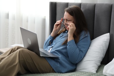 Photo of Woman with vision problem using laptop on bed at home