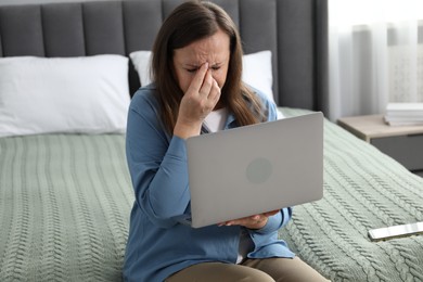 Photo of Woman with vision problem using laptop on bed at home