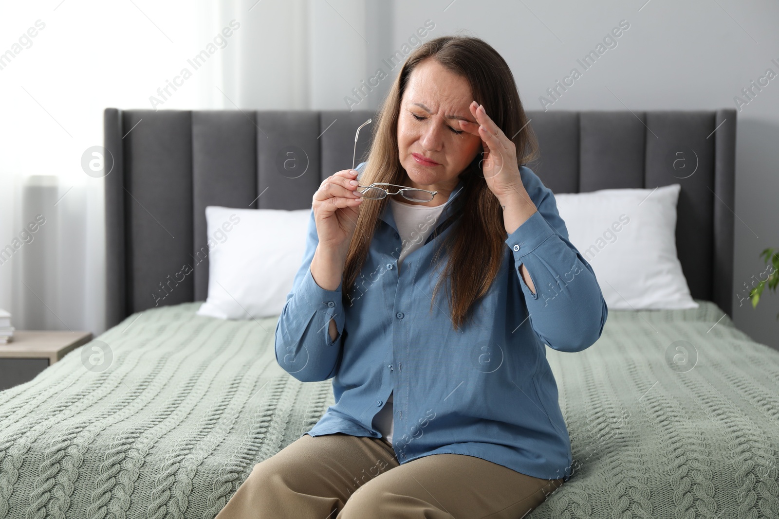 Woman with glasses suffering from eyestrain on bed at home Photo of Woman with glasses suffering from eyestrain on bed at home