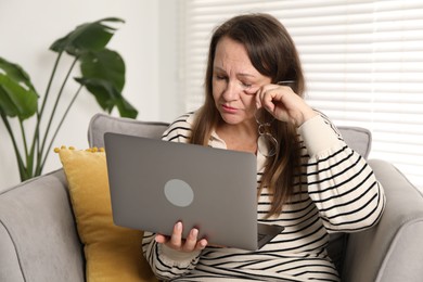 Photo of Woman with vision problem using laptop in armchair at home