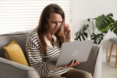 Photo of Woman with vision problem using laptop in armchair at home