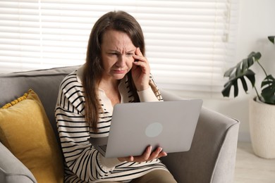Photo of Woman with vision problem using laptop in armchair at home