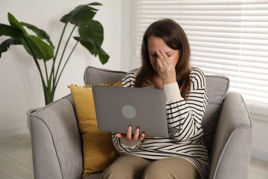Photo of Woman with vision problem using laptop in armchair at home