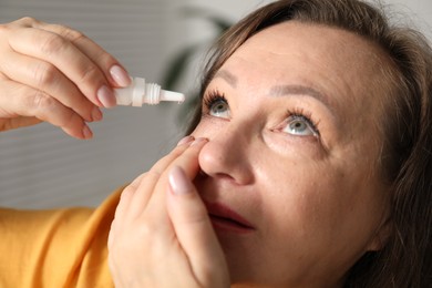 Photo of Woman applying eye drops at home, closeup
