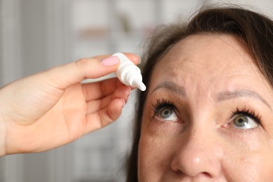 Photo of Daughter dripping medication into mother's eye at home, closeup