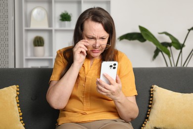 Photo of Woman with vision problem using smartphone on sofa at home