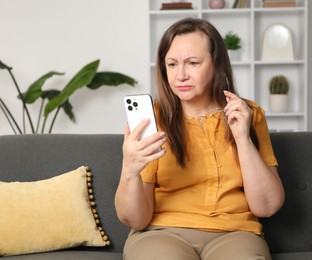 Photo of Woman with vision problem using smartphone on sofa at home