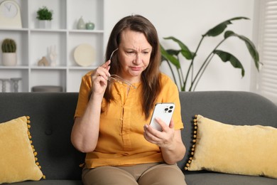 Photo of Woman with vision problem using smartphone on sofa at home