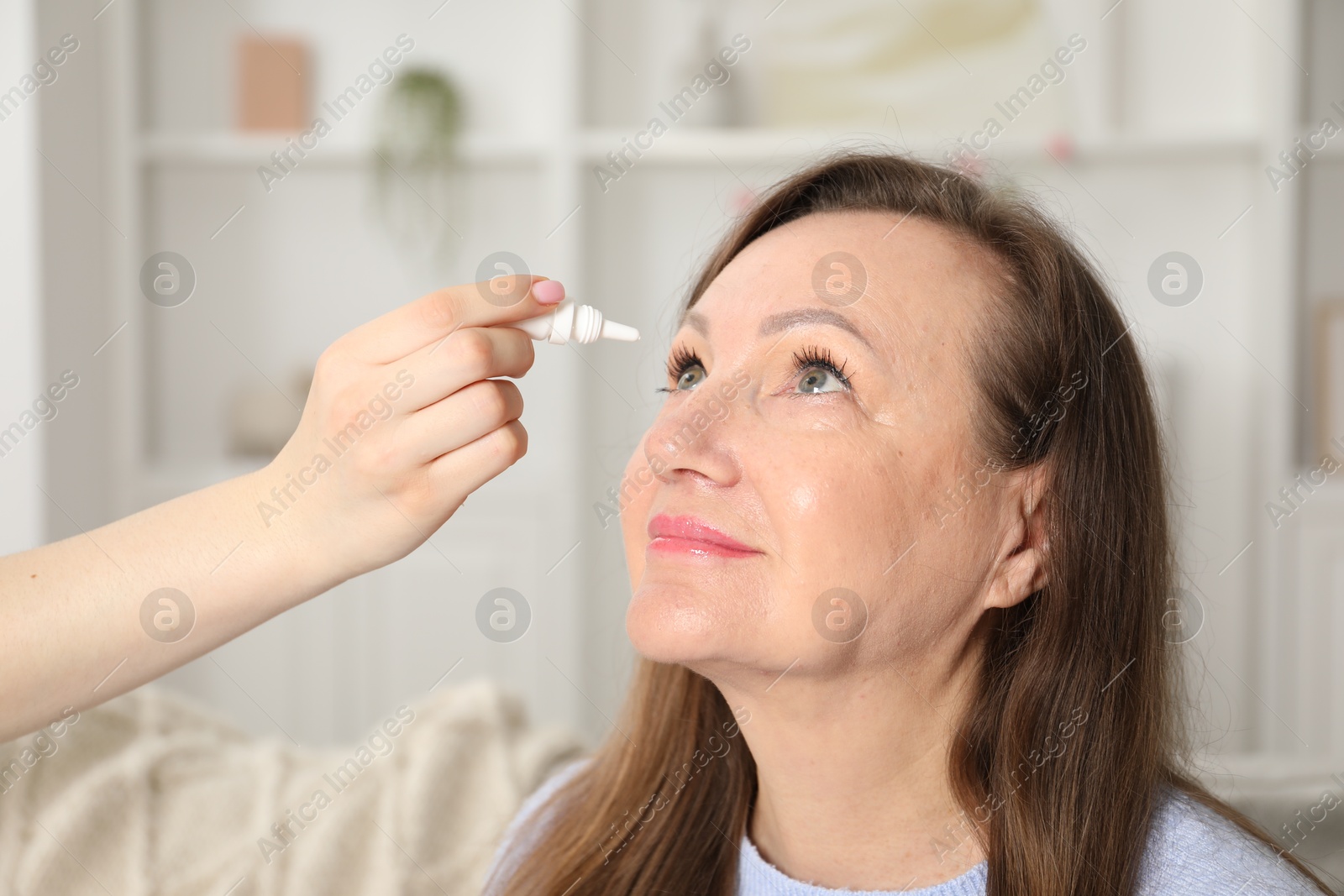 Daughter dripping medication into mother's eye at home, closeup Photo of Daughter dripping medication into mother's eye at home, closeup