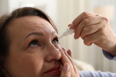 Photo of Woman applying eye drops at home, closeup