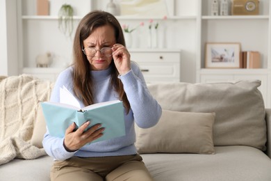 Photo of Woman with vision problem reading book on sofa at home, space for text