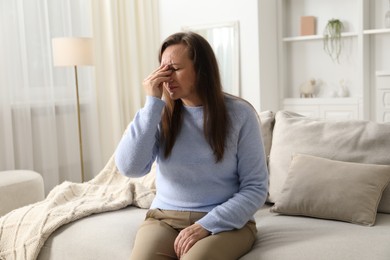 Photo of Woman suffering from eyestrain on sofa at home