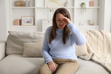 Photo of Woman suffering from eyestrain on sofa at home