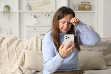 Photo of Woman with vision problem using smartphone on sofa at home