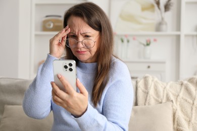 Photo of Woman with vision problem using smartphone on sofa at home