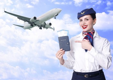 Image of Happy stewardess pointing at passport with flight tickets against sky and plane