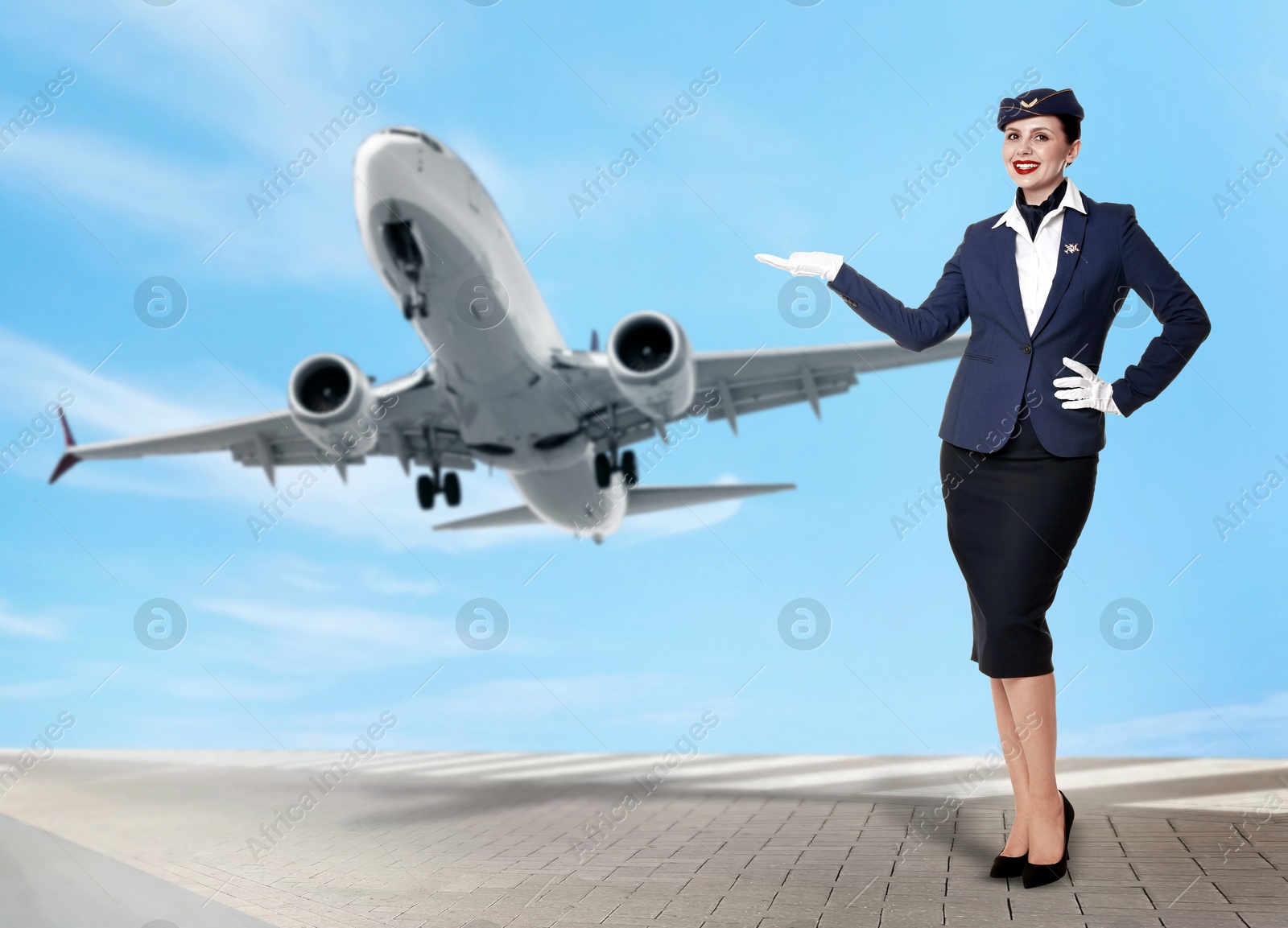 Smiling stewardess pointing at plane against blue sky with clouds Image of Smiling stewardess pointing at plane against blue sky with clouds