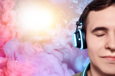 Image of Young man listening to music with headphones against universe