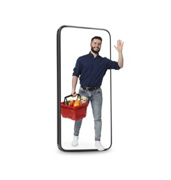 Image of Happy man with shopping basket walking out of mobile phone on white background. Online ordering
