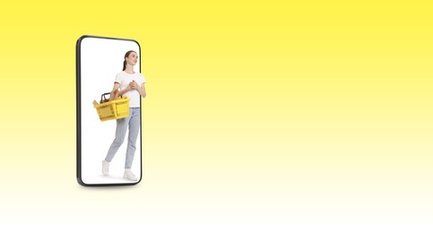 Image of Happy woman with shopping basket walking out of mobile phone on yellow gradient background, banner design. Online order