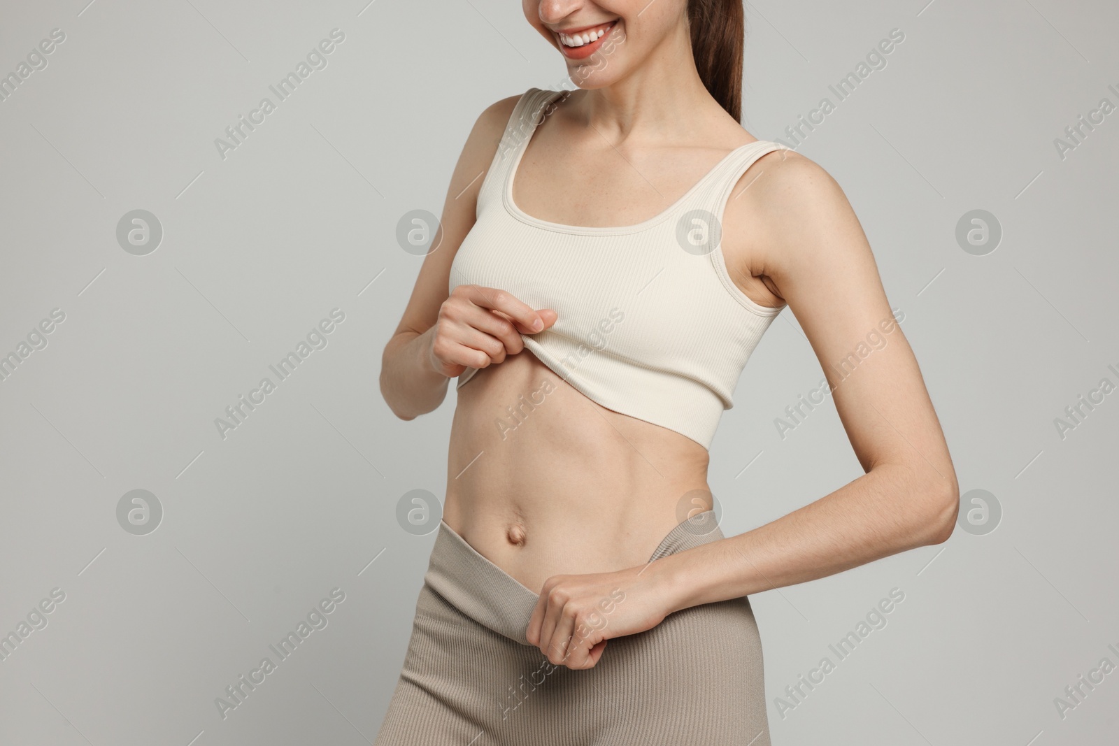 Beautiful woman with flat belly on gray background, closeup Photo of Beautiful woman with flat belly on gray background, closeup