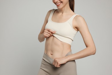 Photo of Beautiful woman with flat belly on gray background, closeup