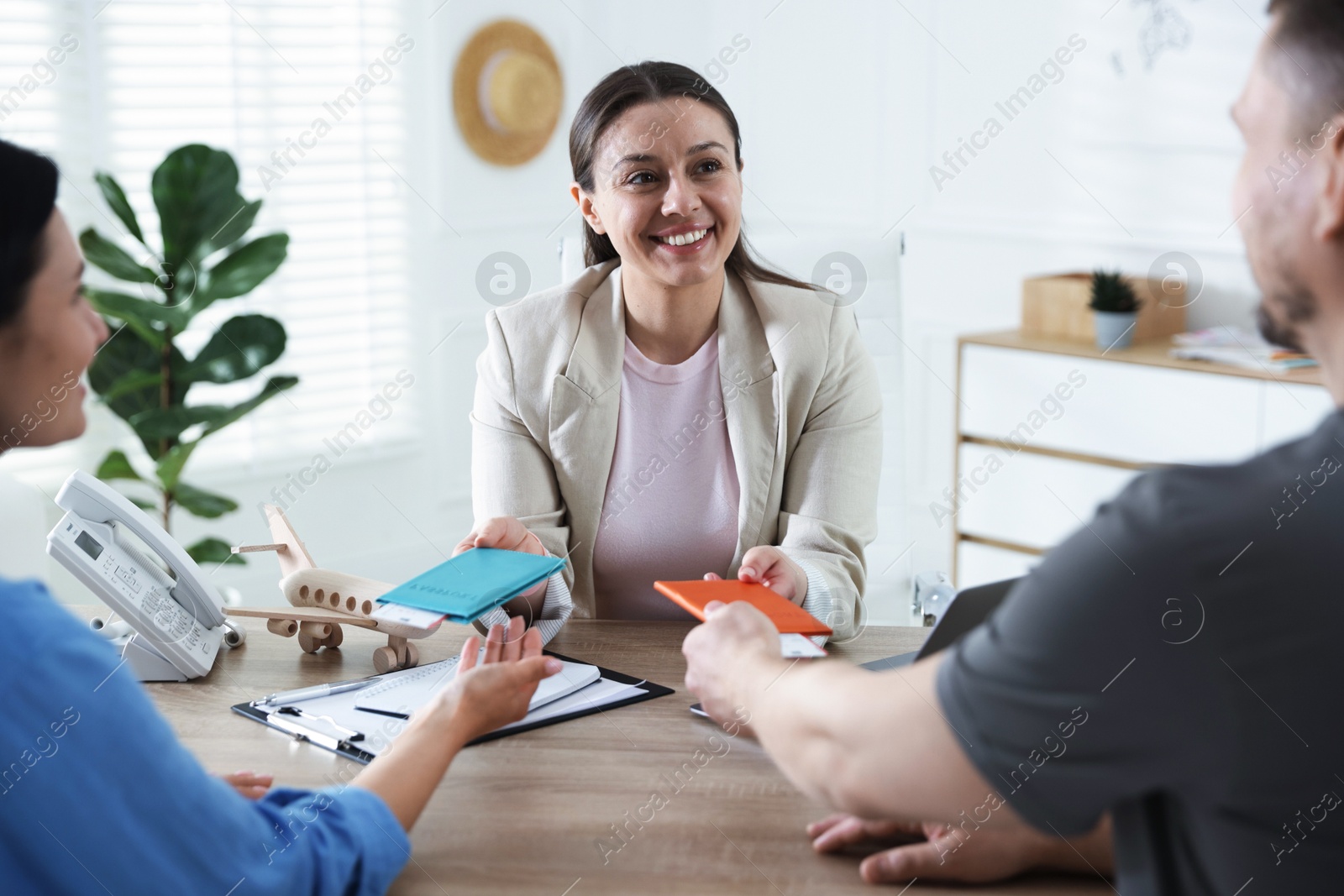 Photo of Happy couple planning vacation with travel agent at wooden table in office